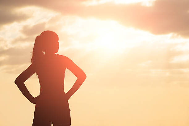 silhouette of woman look silhouette of woman look and think with sunlight hand on hip stock pictures, royalty-free photos & images