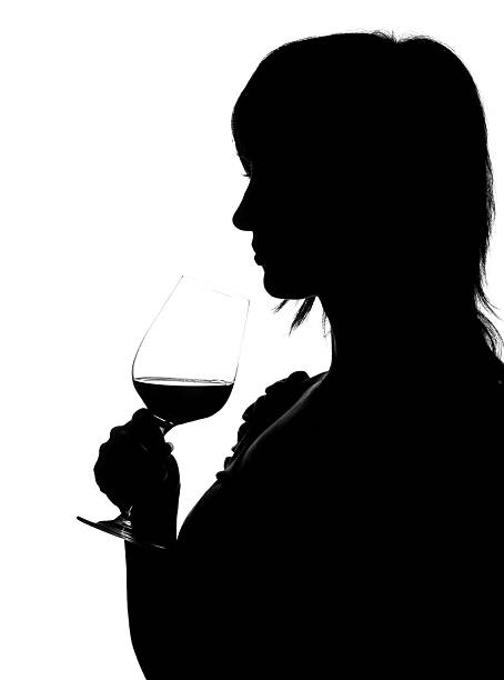 Silhouette of woman smelling red wine stock photo