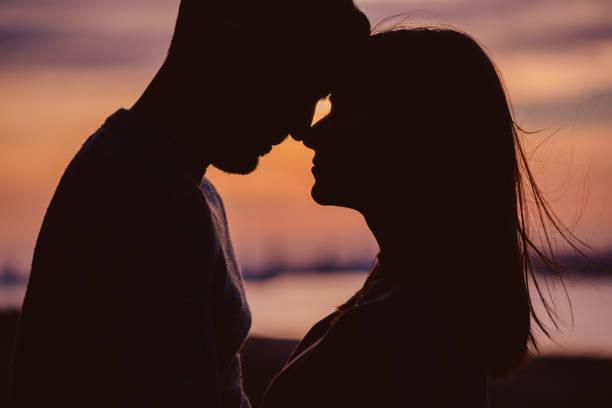 silhouette di giovane coppia con momenti romantici sullo sfondo del tramonto - couple kiss foto e immagini stock