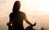 istock Silhouette of young woman practicing yoga outdoors 1321664779