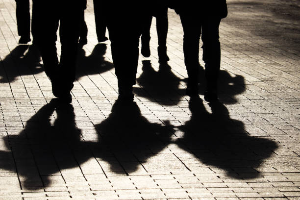 Silhouettes and shadows of people on the city street Crowd walking down on sidewalk, concept of strangers, crime, society, gang or population gang stock pictures, royalty-free photos & images