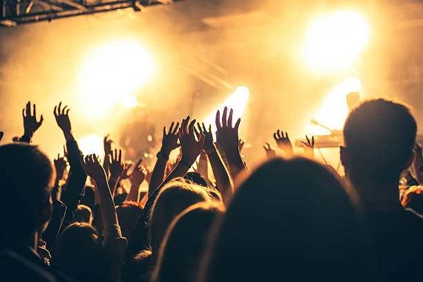 silhouettes of concert crowd in front of bright stage lights - concert stockfoto's en -beelden