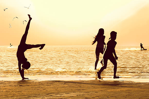 Silhouettes of girls on the beach at sunset stock photo