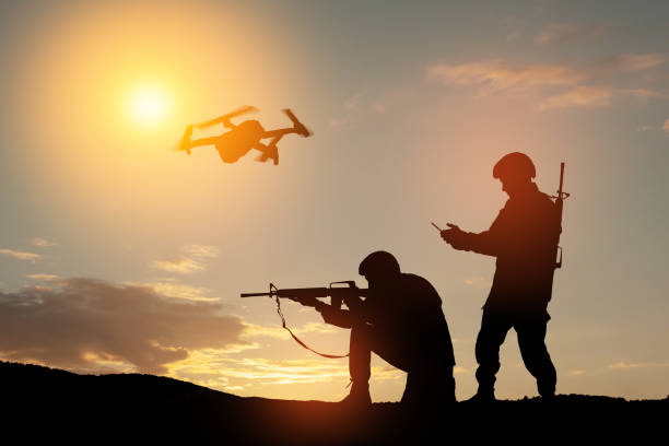 Silhouettes of soldiers are using drone and laptop computer for scouting during military operation. stock photo