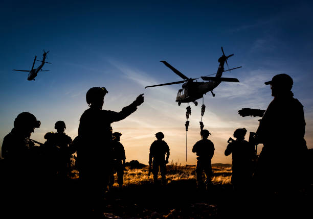 Silhouettes of soldiers on Military Mission at dusk stock photo