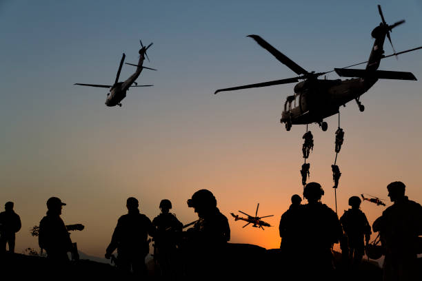 Silhouettes of soldiers on Military Mission at dusk ATTENTION FOR INSPECTOR: This is a composite image and some models were used multiple times in the photo. There are 13 people on the photo, but actually there were just 6 models on the shoot. That's why, I uploaded 6 model release. Please consider this.  

Silhouettes of soldiers on Military Mission at dusk military helicopter stock pictures, royalty-free photos & images