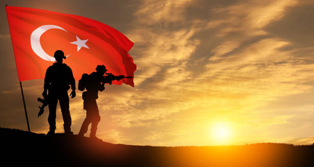 Silhouettes of soldiers with Turkey flag on background of sunset. stock photo