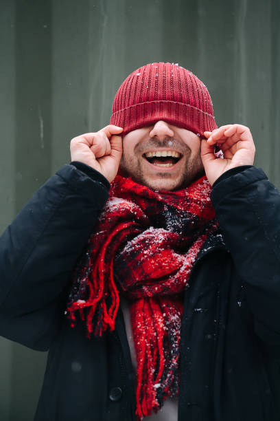 Silly portrait of a positive middle age man with winter hat over his eyes stock photo