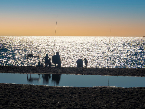 Silueta de una familia pescando en la orilla de la playa de Salobreña