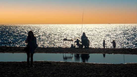 Silueta de una familia pescando en la orilla de la playa de Salobreña