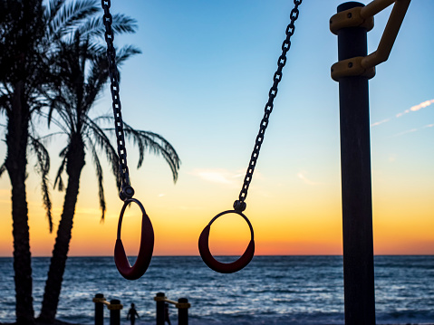 Siluetas de anillas de gimnasia frente al mar al atardecer