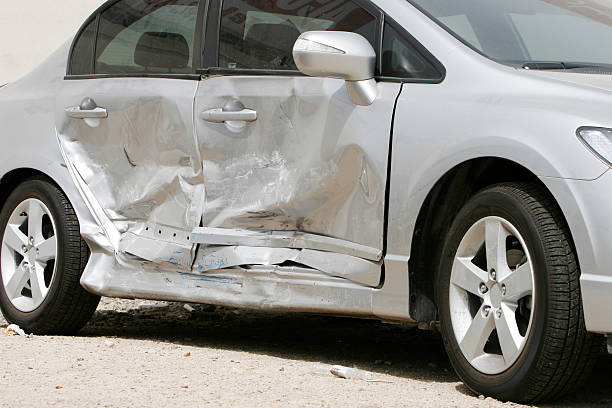 Silver car with a large dent in the side, ruining two doors Side impact crash. dented stock pictures, royalty-free photos & images