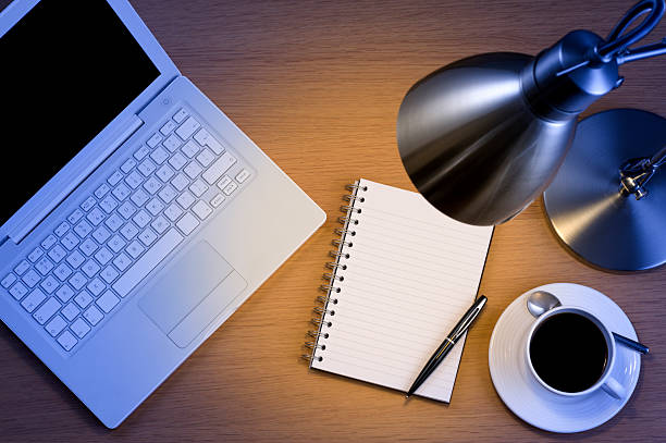Silver desk lamp laptop pen and notepad and black coffee stock photo