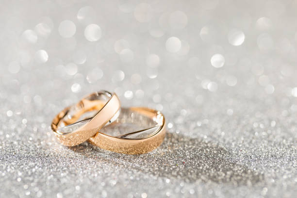 Silver sparkling glitter bokeh background with golden wedding rings Silver sparkling glitter bokeh background with golden wedding rings. Shallow focus. Copy space wedding anniversary stock pictures, royalty-free photos & images