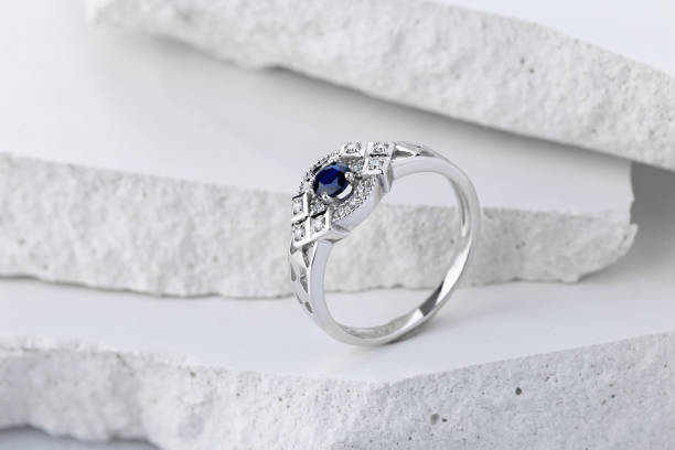 Silver wedding ring decorated with sapphire and diamonds Silver wedding ring decorated with sapphire and diamonds on white background. Vintage style white gold engagement ring with blue gemstone zoisite stock pictures, royalty-free photos & images