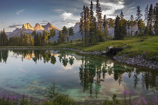 Peaceful Pond in Famous Silvertip Golf Course above Town of Canmore with Reflections of Three Sisters Mountain near entrance to Banff National Park in Rocky Mountains Alberta Canada