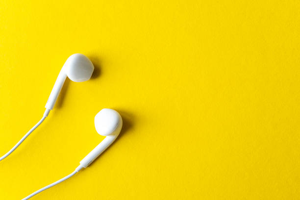 Simple flat lay composition with white headphones on bright yellow background, top view, space for text or ideas stock photo