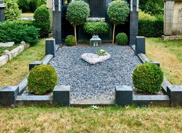 Simple nobly designed minimalist grave with gravel and buxus bushes in the main cemetery stock photo