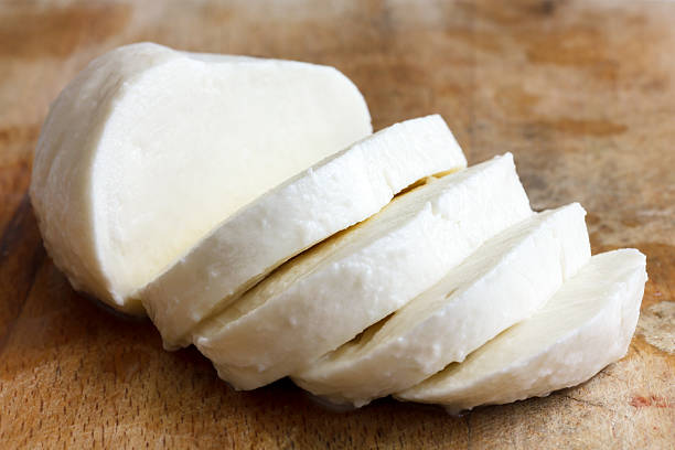 Single ball of mozzarella cheese sliced and isolated on rustice Single ball of mozzarella cheese sliced and isolated on rustice wood. mozzarella stock pictures, royalty-free photos & images