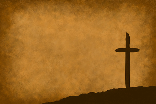 A single religious cross of Calvary on the right bottom area on a weathered antique parchment paper background.  The Christian cross shape is a symbol representing love, peace, hope and forgiveness and is a spiritual symbol of the resurrection of Christ, used often at Easter, Good Friday and Christmas holiday celebrations.