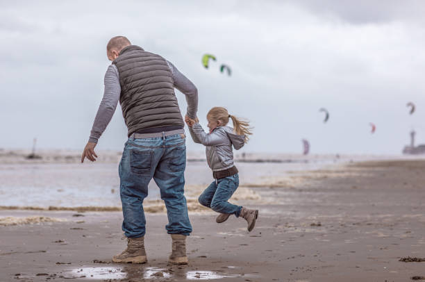 Single father and his daughter playing family games on a winter beach Handsome redhead single father and his blonde daughter playing family games on a winter beach divorce beach stock pictures, royalty-free photos & images
