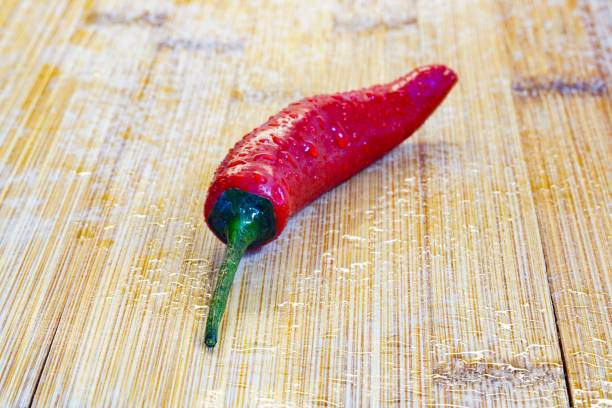 Single red chilli pepper on a chopping board stock photo