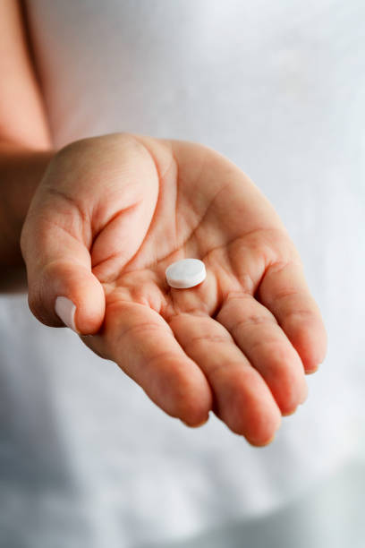 pilule d’aspirine blanc unique sur les mains de la jeune femme - pilule du lendemain photos et images de collection