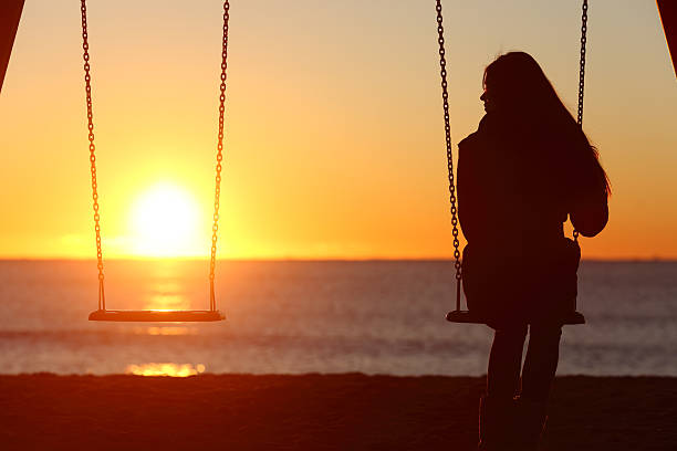 Single woman alone swinging on the beach Single woman alone swinging on the beach and looking the other seat missing a boyfriend mourner stock pictures, royalty-free photos & images