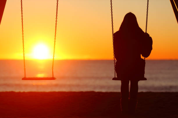 Single woman sitting on a swing contemplating sunset Single woman sitting on a swing contemplating sunset divorce beach stock pictures, royalty-free photos & images