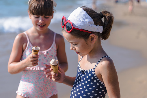 Happy young girls having an ice cream at their day at the beach