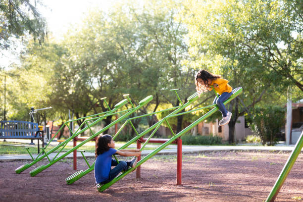 Sisters playing on a seesaw together stock photo