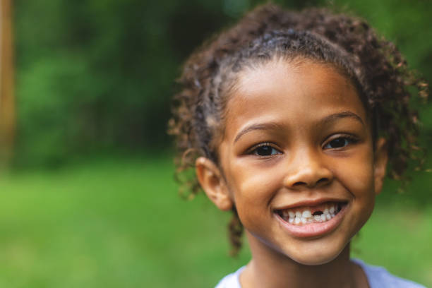 six year old african american chinese ethnicity girl posing for portrait in lush green outdoor back yard setting - foster kids imagens e fotografias de stock
