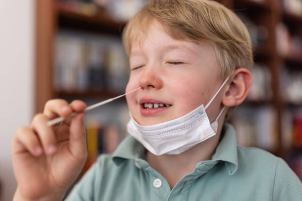 Six year old school boy carrying out self test against coronavirus stock photo