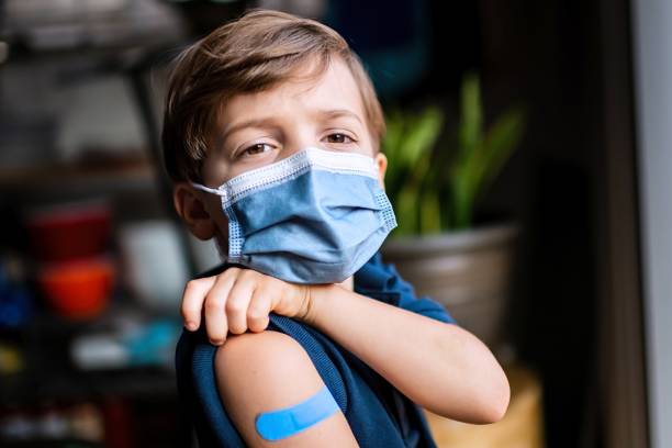 Six years old child showing his band aid just after being vaccinated stock photo