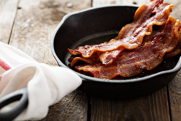 sizzling hot bacon in a cast iron skillet - bacon bildbanksfoton och bilder