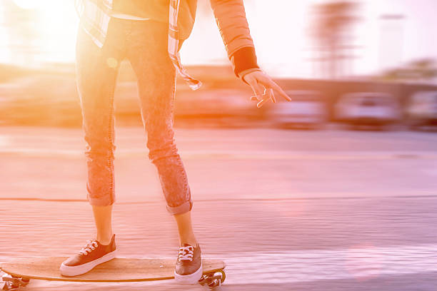 skater girl in motion on street at sunset stock photo