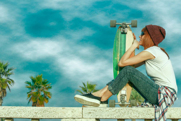 skater girl relaxing and holding her long board stock photo