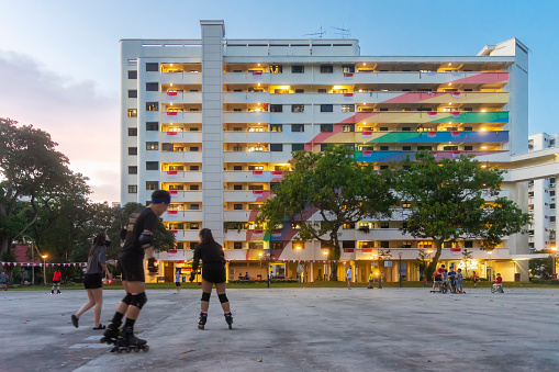 Singapore, Singapore - August 9, 2021: A group of rollerbladers before a public HDB residential block in Hougang, with a large mural of a rainbow painted across its facade.