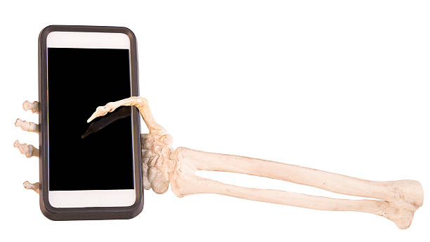 skelett hand holding handy - menschliches skelett stock-fotos und bilder