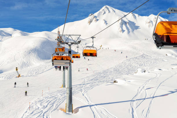 ski lift ropeway on hilghland alpine mountain winter resort on bright sunny day. ski chairlift cable way with people enjoy skiing and snowboarding.banner panoramic wide view of downhill slopes - esqui esqui e snowboard imagens e fotografias de stock