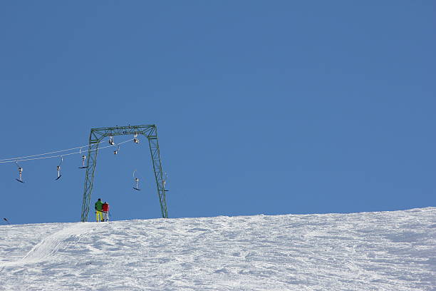 Skier at the T-bar lift, Ski Slope Kühtai, Austria - February 6, 2014: Two skier use a T-bar lift direct at the the ski slope. They are a colorful dot in the the white winter landscape. t bar ski lift stock pictures, royalty-free photos & images