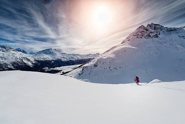 Skier skiing downhill in high mountains against sunset stock photo