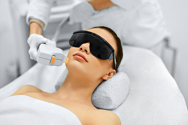 Skin Care. Face Beauty Treatment. IPL. Photo Facial Therapy. Ant Skin Care. Young Woman Receiving Facial Beauty Treatment, Removing Pigmentation At Cosmetic Clinic. Intense Pulsed Light Therapy. IPL. Rejuvenation, Photo Facial Therapy. Anti-aging Procedures. laser stock pictures, royalty-free photos & images