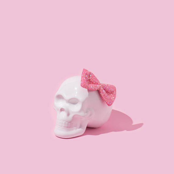 Skull with pink bow tie. Minimal spooky girl concept. Halloween pink background. human skeleton photos stock pictures, royalty-free photos & images