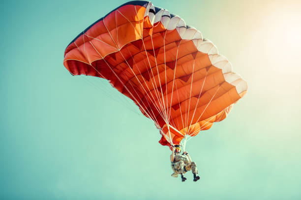 Skydiver On Colorful Parachute In Sunny Clear Sky. stock photo