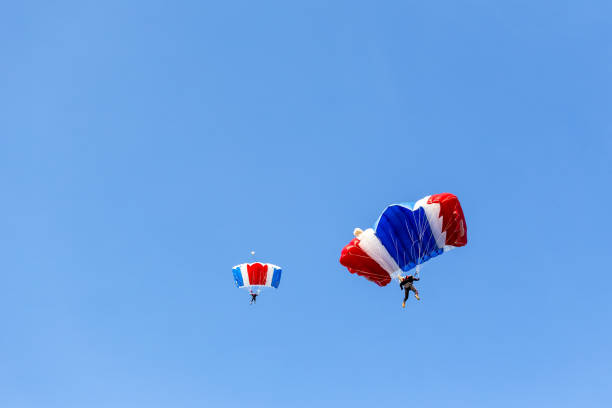 skydiver team in colorful parachute gliding after free fall jump with blue sky background stock photo