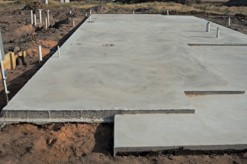 Concrete slab prepared for residential house construction with utility pipes within slab