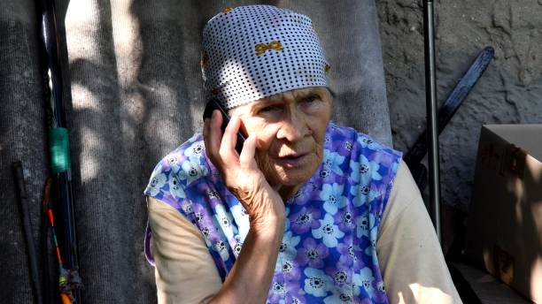 Slavic senior rural woman using phone at village stock photo
