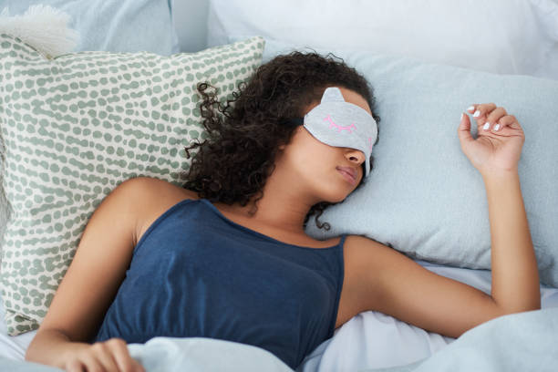 I sleep better with my eye mask on Shot of an attractive young woman sleeping in bed with an eye mask during the morning eye mask stock pictures, royalty-free photos & images