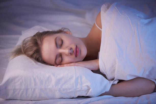 sleeping girl on an orthopedic pillow with night lighting, white linens stock photo